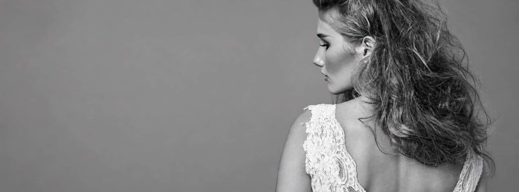 Dos d’une robe de mariée en dentelle, photographie en noir et blanc.